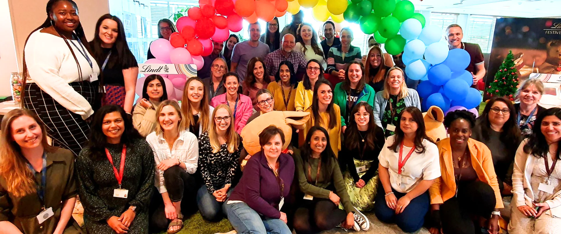 Group of smiling coworkers, under balloon arch in an office